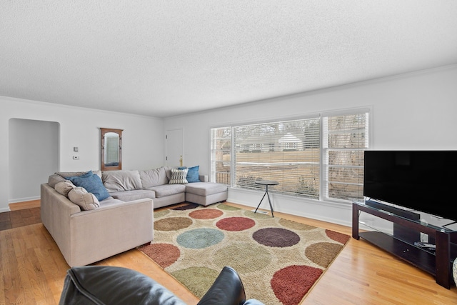 living area with crown molding, wood finished floors, baseboards, and a textured ceiling