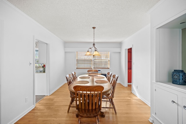 dining space featuring crown molding, light wood-style flooring, and a textured ceiling