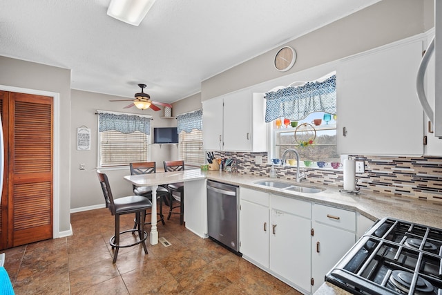 kitchen with backsplash, dishwasher, light countertops, white cabinetry, and a sink