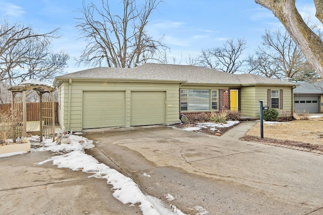 ranch-style home with a garage, brick siding, concrete driveway, and fence