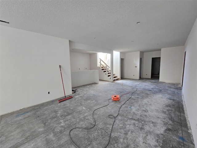 unfurnished room featuring stairs and a textured ceiling