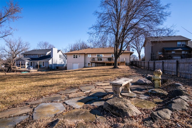 back of house featuring a yard, a chimney, fence, a residential view, and a wooden deck