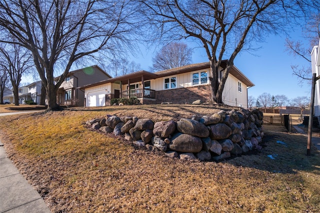 ranch-style house featuring a porch, a garage, brick siding, fence, and board and batten siding