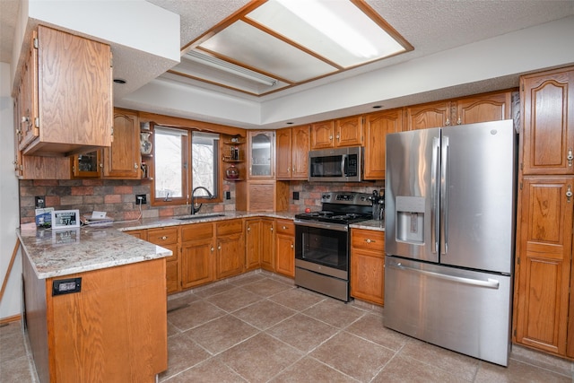 kitchen with appliances with stainless steel finishes, a sink, and brown cabinets