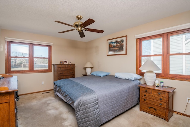 bedroom featuring light carpet, multiple windows, baseboards, and a textured ceiling