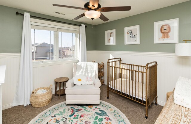14201 Brookview Dr, Urbandale, IA 50323 - carpeted bedroom with a crib, wainscoting, and ceiling fan