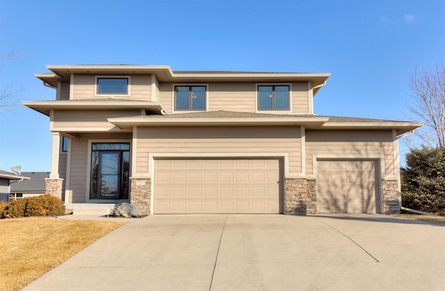 prairie-style house featuring a garage, stone siding, and concrete driveway