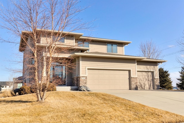 prairie-style home featuring stone siding, a front lawn, and concrete driveway