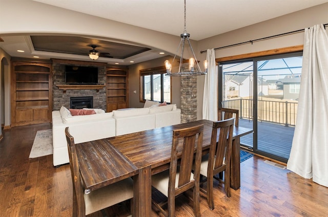 14201 Brookview Dr, Urbandale, IA 50323 - dining area with arched walkways, a ceiling fan, a fireplace, dark wood finished floors, and built in features