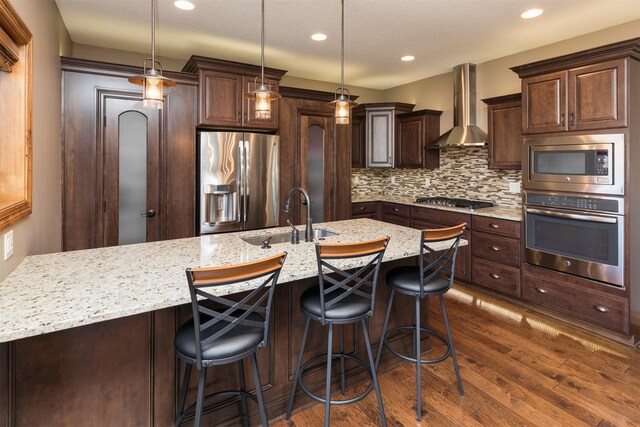 14201 Brookview Dr, Urbandale, IA 50323 - kitchen with appliances with stainless steel finishes, a sink, wall chimney exhaust hood, dark brown cabinetry, and dark wood-type flooring