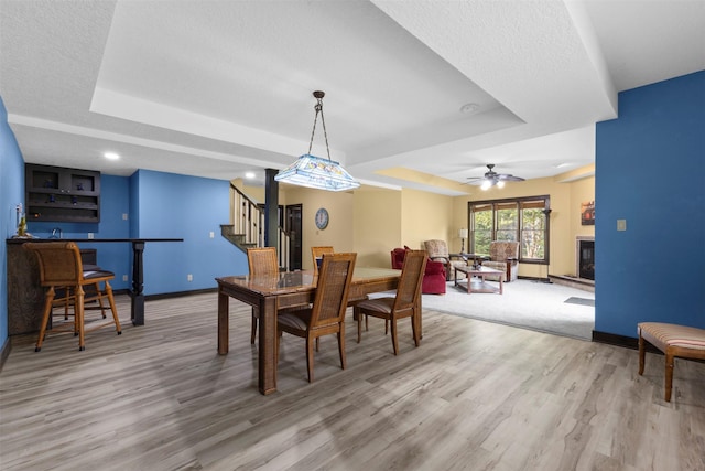 1905 W Olive St, Marshalltown, IA 50158 - dining space with a raised ceiling, stairs, light wood-type flooring, and baseboards