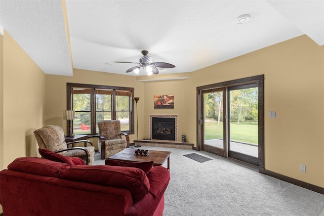 1905 W Olive St, Marshalltown, IA 50158 - carpeted living area featuring a tiled fireplace, plenty of natural light, a ceiling fan, and baseboards