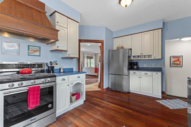 1905 W Olive St, Marshalltown, IA 50158 - kitchen featuring appliances with stainless steel finishes, custom exhaust hood, dark countertops, dark wood-style flooring, and white cabinetry
