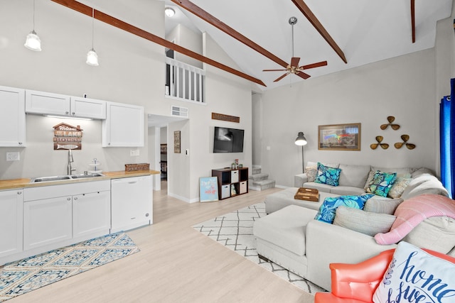 living area with stairs, ceiling fan, light wood finished floors, and high vaulted ceiling