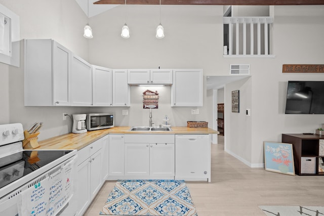 kitchen featuring visible vents, white cabinetry, a sink, high vaulted ceiling, and white appliances