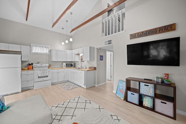 kitchen featuring light countertops, white appliances, light wood-type flooring, and hanging light fixtures