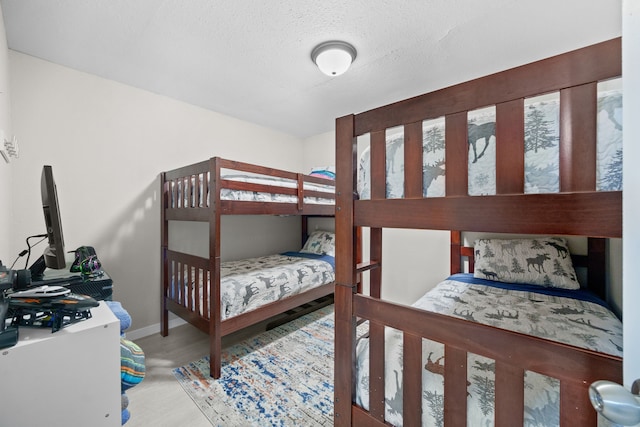 bedroom with a textured ceiling, wood finished floors, and baseboards