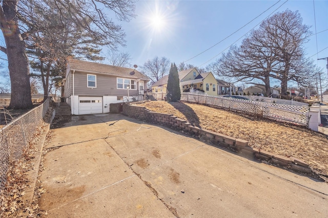 rear view of house featuring driveway, an attached garage, a residential view, and fence