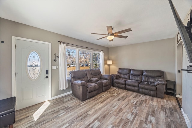 living room featuring baseboards, ceiling fan, and light wood finished floors