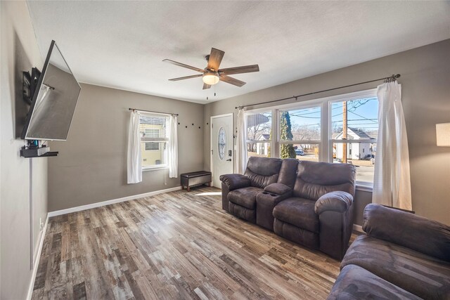 living room with ceiling fan, a textured ceiling, wood finished floors, and baseboards