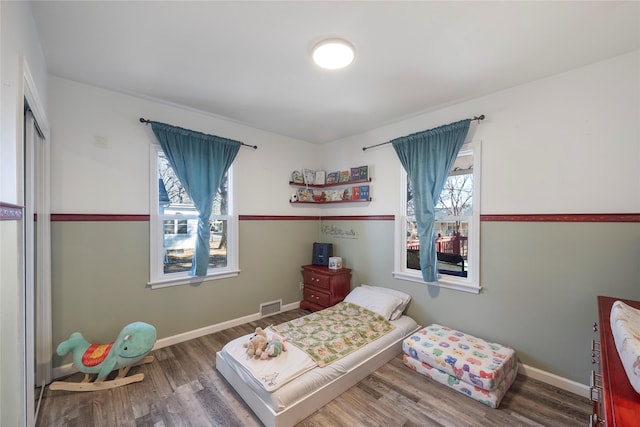 bedroom featuring baseboards, a closet, visible vents, and wood finished floors