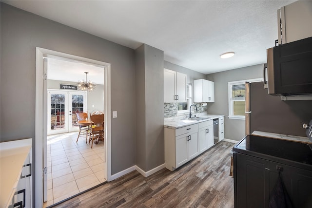 kitchen with tasteful backsplash, white cabinets, dark wood-type flooring, stainless steel appliances, and a sink