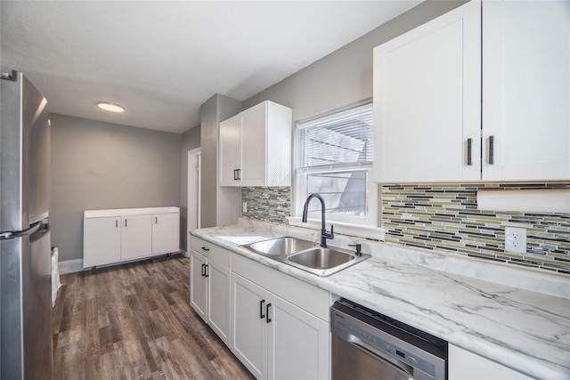 kitchen featuring dark wood finished floors, backsplash, appliances with stainless steel finishes, white cabinets, and a sink