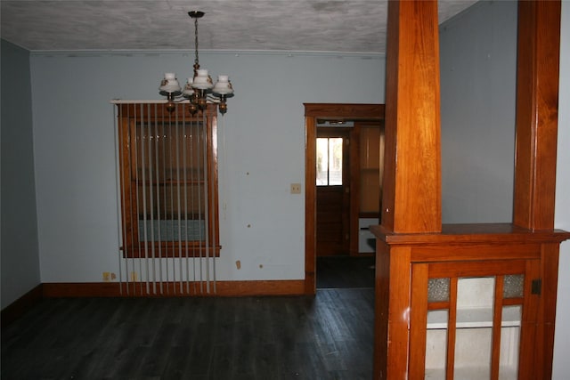 spare room with baseboards, wood finished floors, and an inviting chandelier