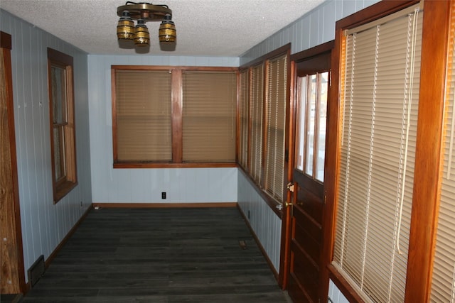 interior space with a textured ceiling, dark wood-type flooring, a notable chandelier, and baseboards