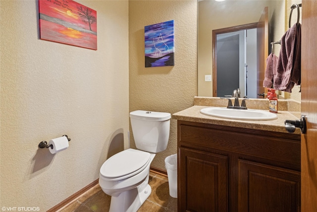 bathroom with a textured wall, vanity, toilet, and tile patterned floors