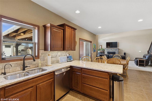 kitchen with open floor plan, a fireplace, a sink, and stainless steel dishwasher