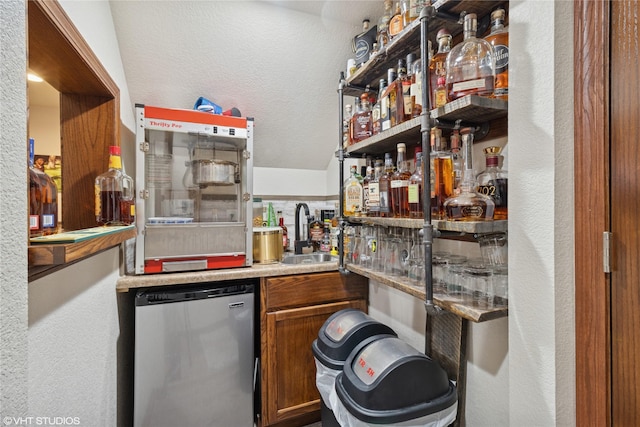 bar featuring a textured wall, indoor bar, a sink, and dishwashing machine