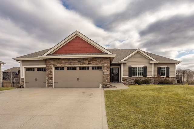 craftsman-style house featuring a garage, a front yard, concrete driveway, and stone siding