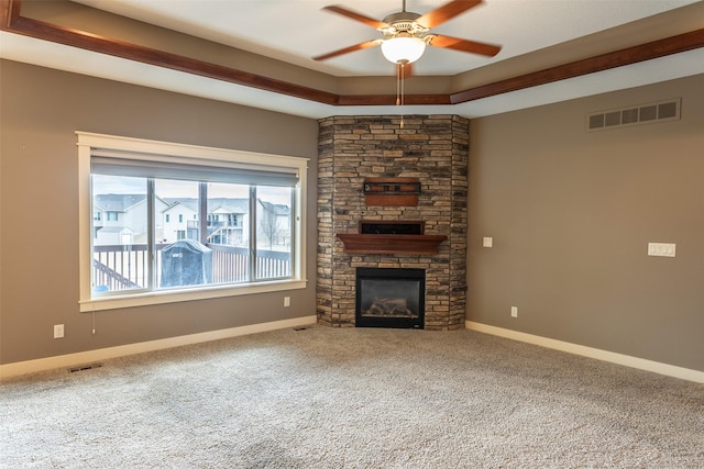 unfurnished living room featuring carpet flooring, a fireplace, a raised ceiling, and visible vents