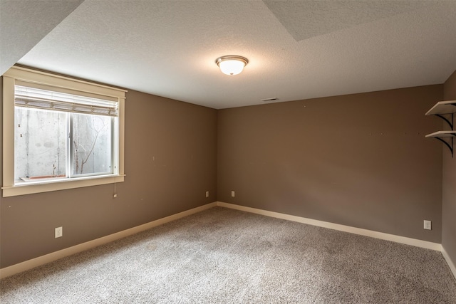 spare room featuring carpet flooring, visible vents, baseboards, and a textured ceiling