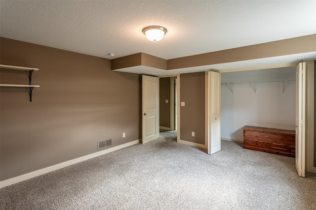 unfurnished bedroom featuring a closet, visible vents, light carpet, a textured ceiling, and baseboards