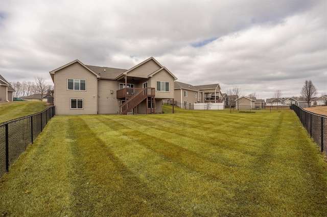 back of property featuring a deck, a fenced backyard, a lawn, and stairway