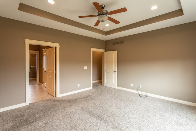 unfurnished bedroom with baseboards, a raised ceiling, and light colored carpet