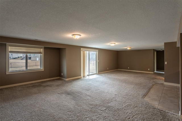 empty room with a textured ceiling, carpet flooring, and baseboards