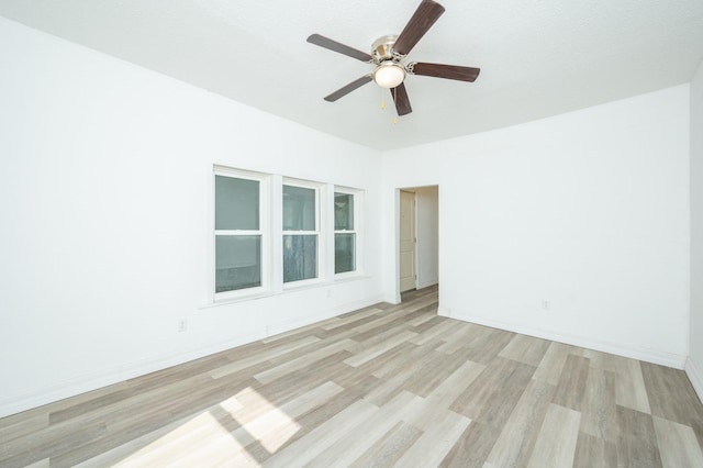 spare room with baseboards, a ceiling fan, and light wood-style floors