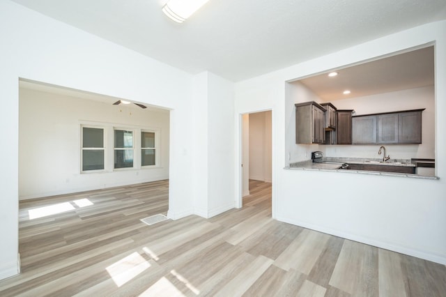 kitchen with light countertops, light wood-style flooring, a sink, and dark brown cabinetry