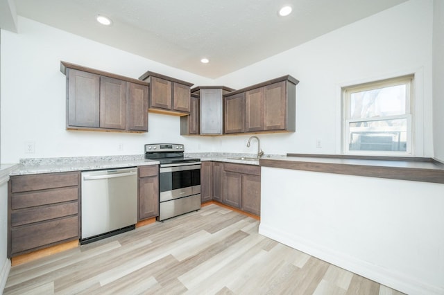 kitchen with light wood finished floors, light countertops, stainless steel appliances, a sink, and recessed lighting