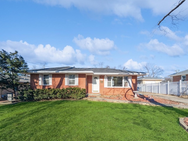 view of front of house with brick siding, a front yard, and fence