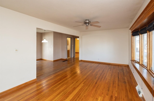 empty room with light wood-style flooring, visible vents, and baseboards