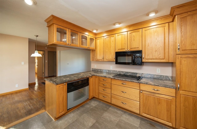 kitchen with a peninsula, baseboards, hanging light fixtures, black appliances, and glass insert cabinets