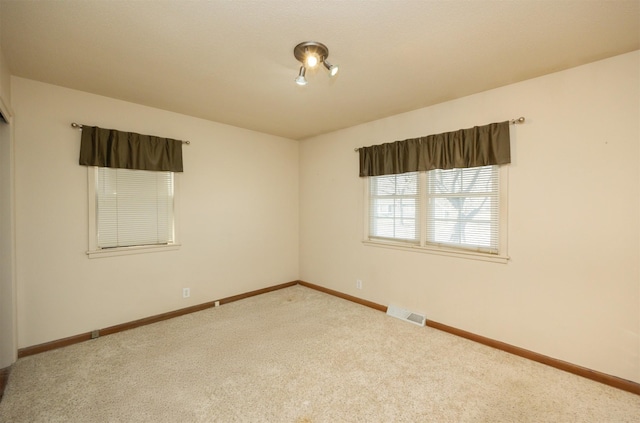 empty room with carpet floors, baseboards, and visible vents