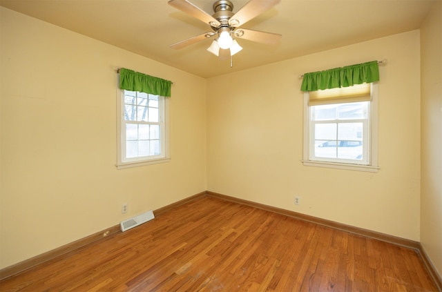 empty room featuring light wood-style flooring, visible vents, and baseboards