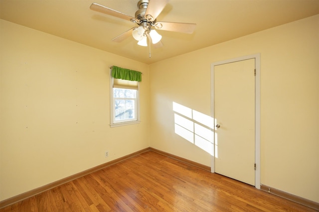 spare room with wood finished floors, a ceiling fan, and baseboards