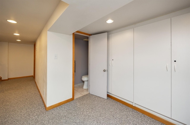 interior space with baseboards, light colored carpet, ensuite bathroom, a closet, and recessed lighting