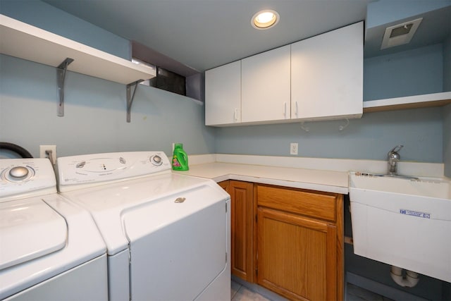 clothes washing area featuring washing machine and dryer, cabinet space, a sink, and visible vents